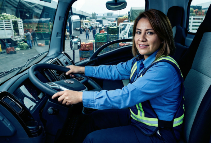 Mujer operadora de tractocamión en la cabina de una unidad ELAM-FAW Trucks, destacando la inclusión y tecnología en el transporte de carga.